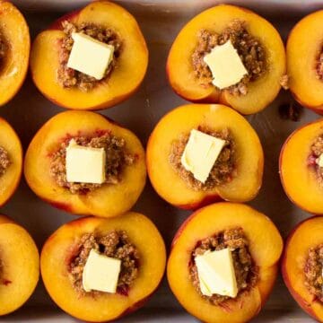 Overhead view of amaretti filled peaches with a small square of butter on each.