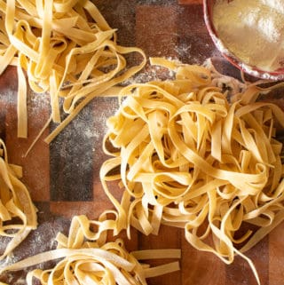 Fresh egg tagliatelle with small red dish of flour