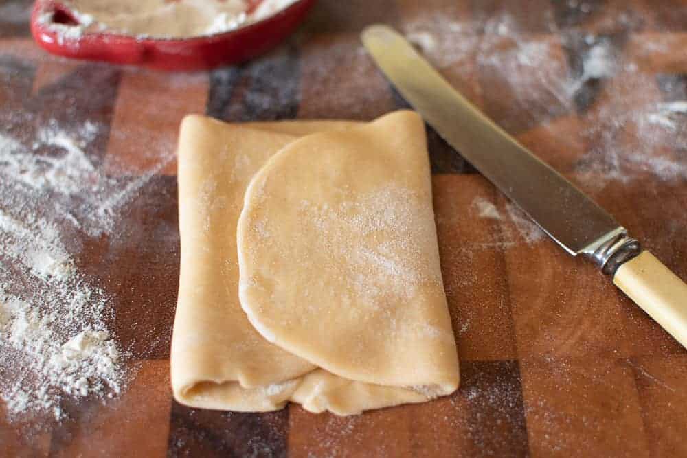 Pasta dough folded, knife and flour.