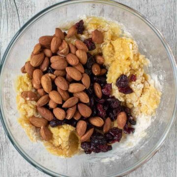 Almonds and dried cranberries being added to dough.