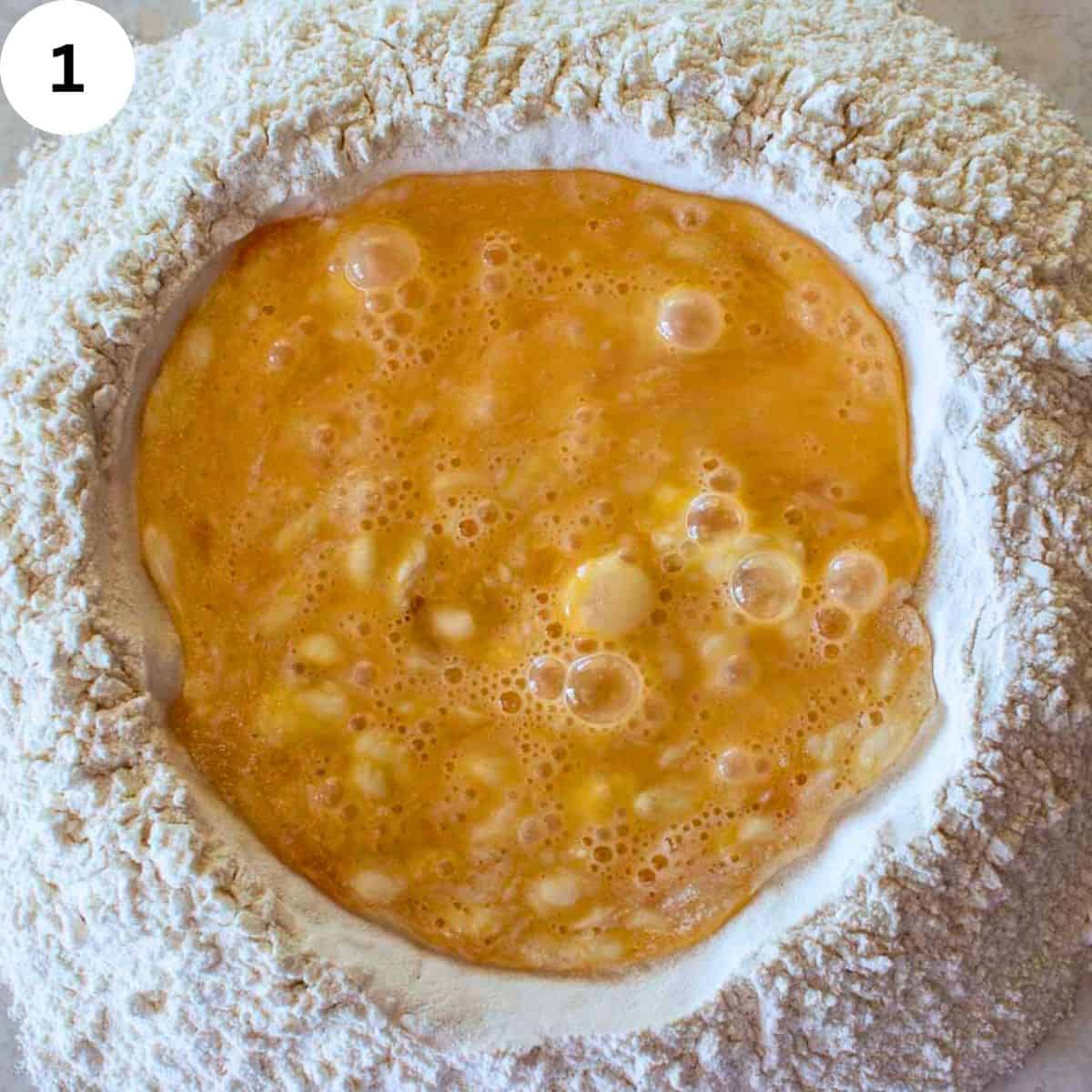 Beaten eggs in the middle of a well of flour.