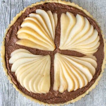 Fanned pear slices on a chocolate filling in a tart viewed from above.
