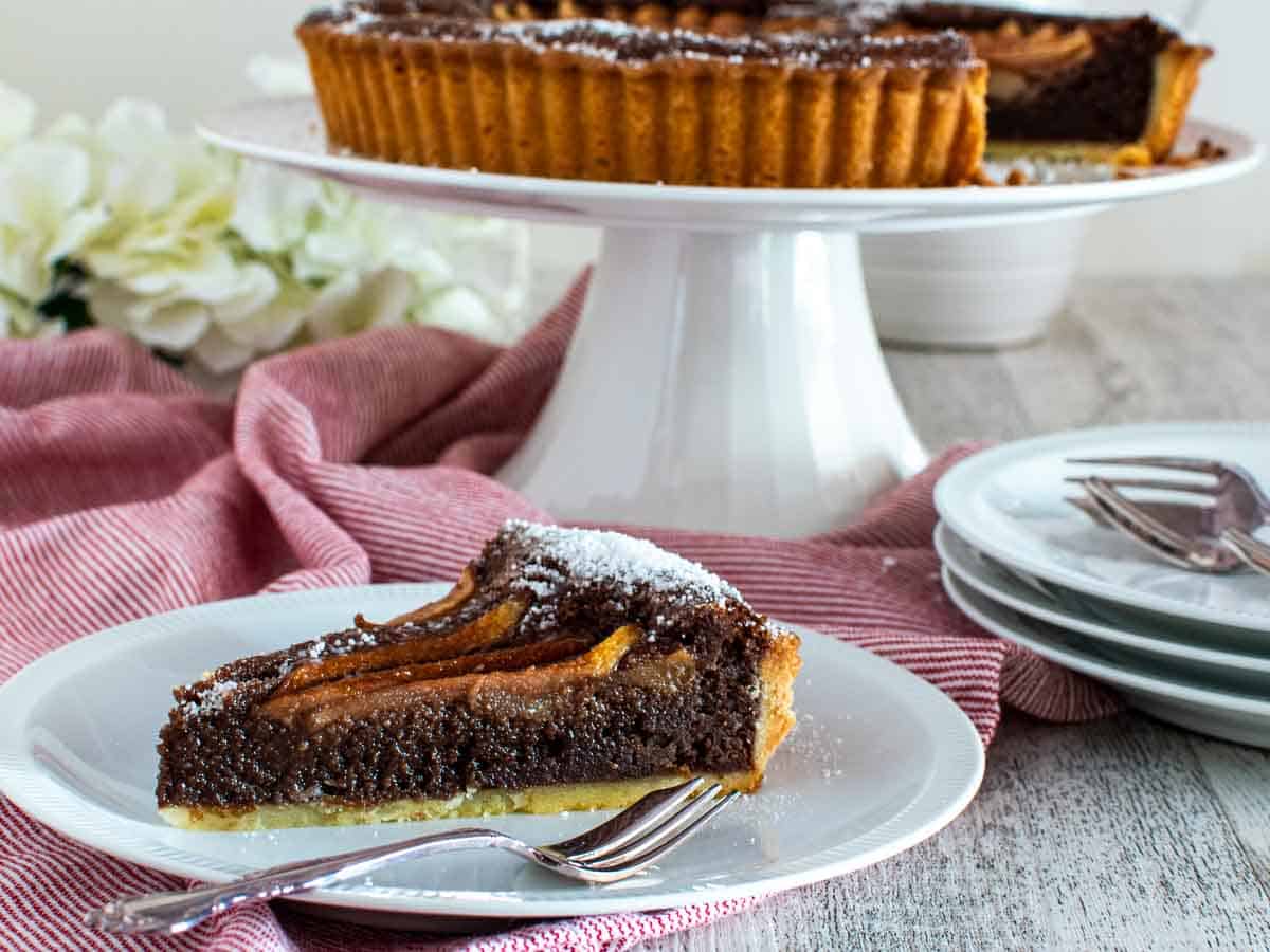 Close up of a slice of chocolate tart on a white plate.