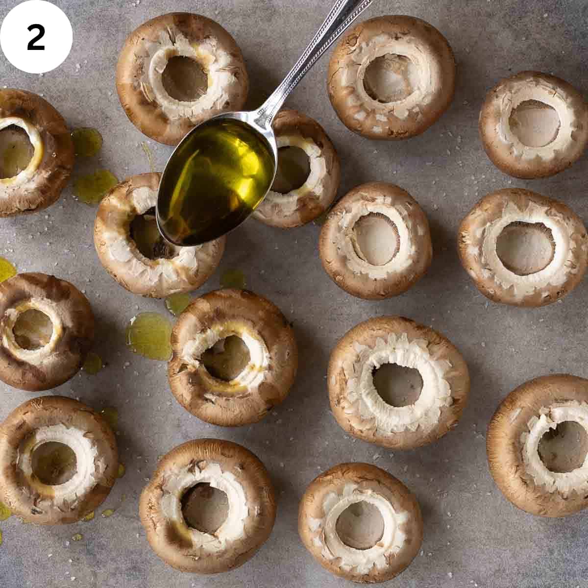 Drizzling olive oil over mushroom caps.