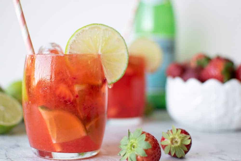 Glass of Strawberry Lime Water with strawberries and second glass behind