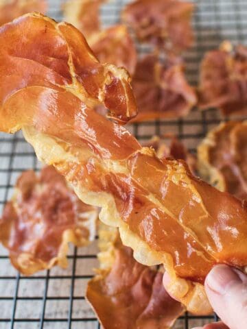 Crispy Prosciutto held by two fingers.