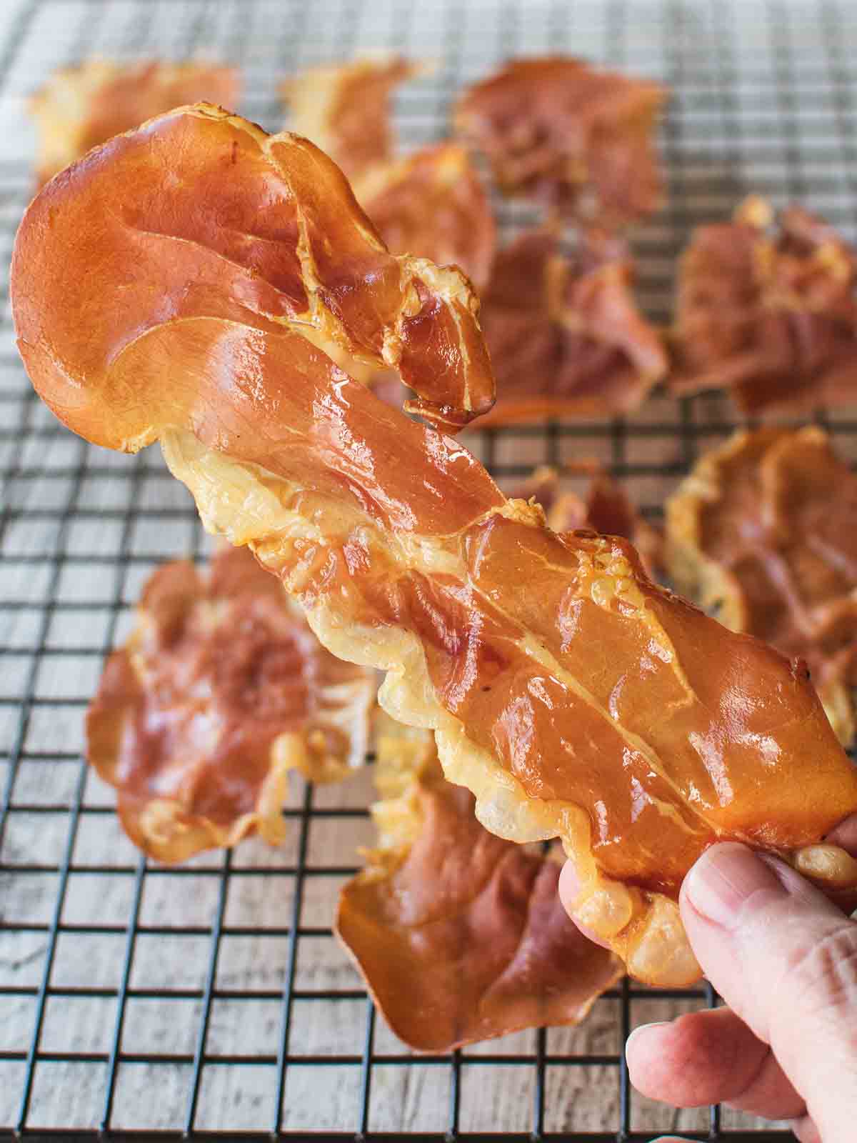 Crispy Prosciutto held by two fingers.