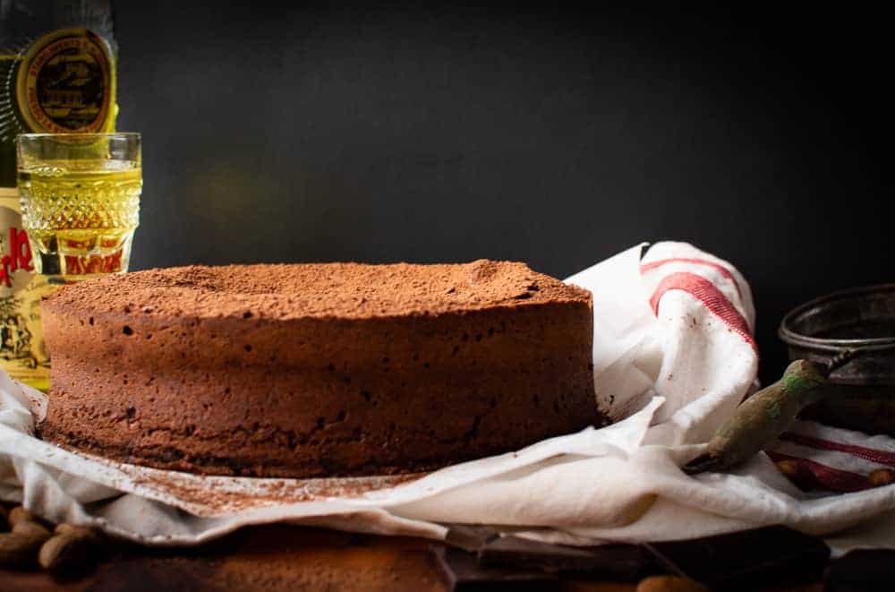 Chocolate almond cake with liqueur bottle and glass in the background