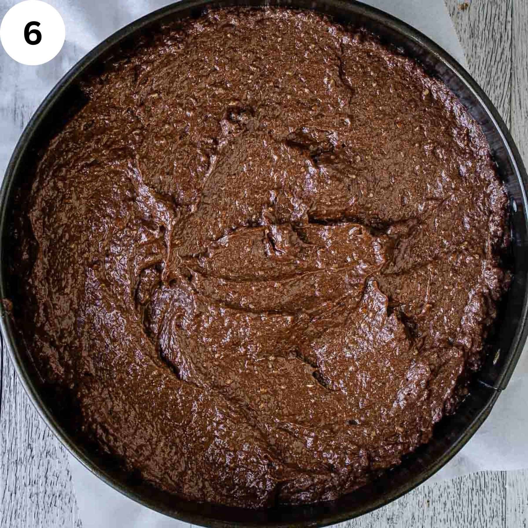 Grainy chocolate cake batter in a round cake pan.