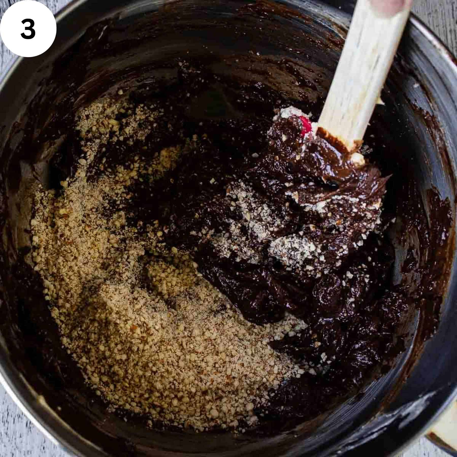 Stirring ground nuts and melted chocolate together.