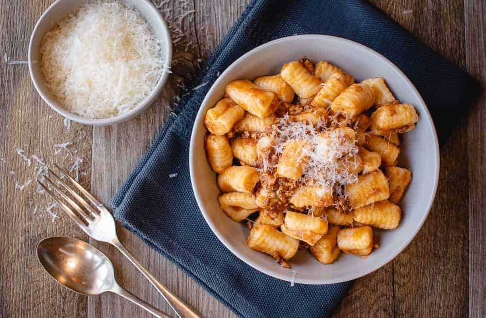 white bowl of gnocchi on blue cloth