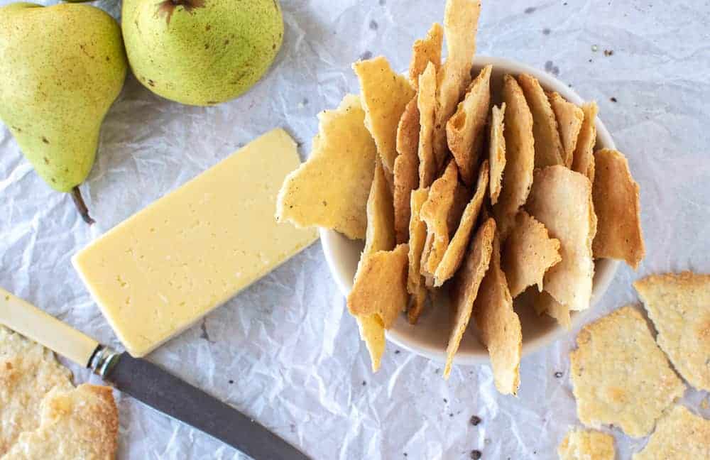 Homemade crackers are simply delicious, easy and so inexpensive to make. #homemadecrackers #crackers #cheese #artisan homemade crackers in white bowl with cheese and green pears