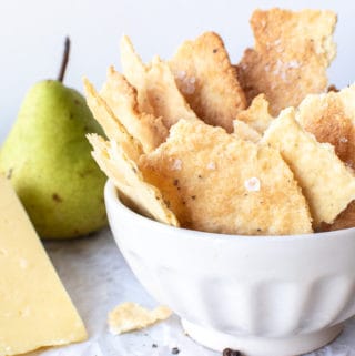 homemade saltines in white bowl with cheese and green pears.