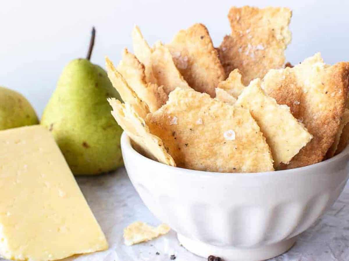 Homemade savory cookies in white bowl with cheese and green pears.