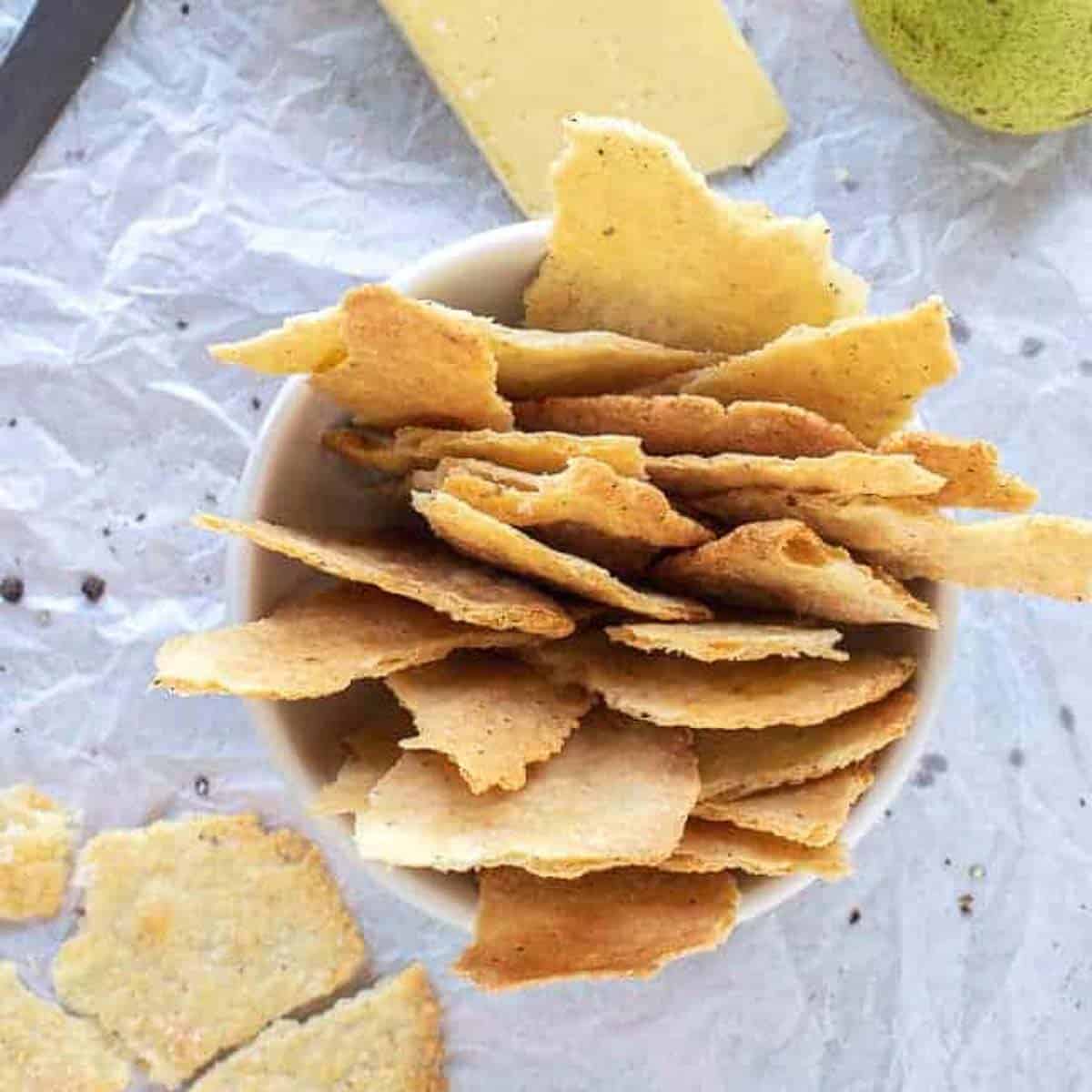 homemade crackers in white bowl with cheese and green pears