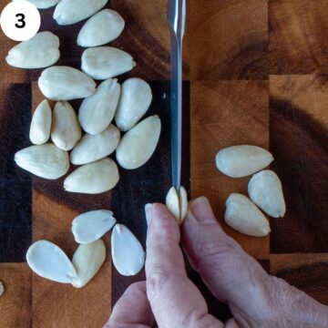 Blanched almonds being halved with a knife.