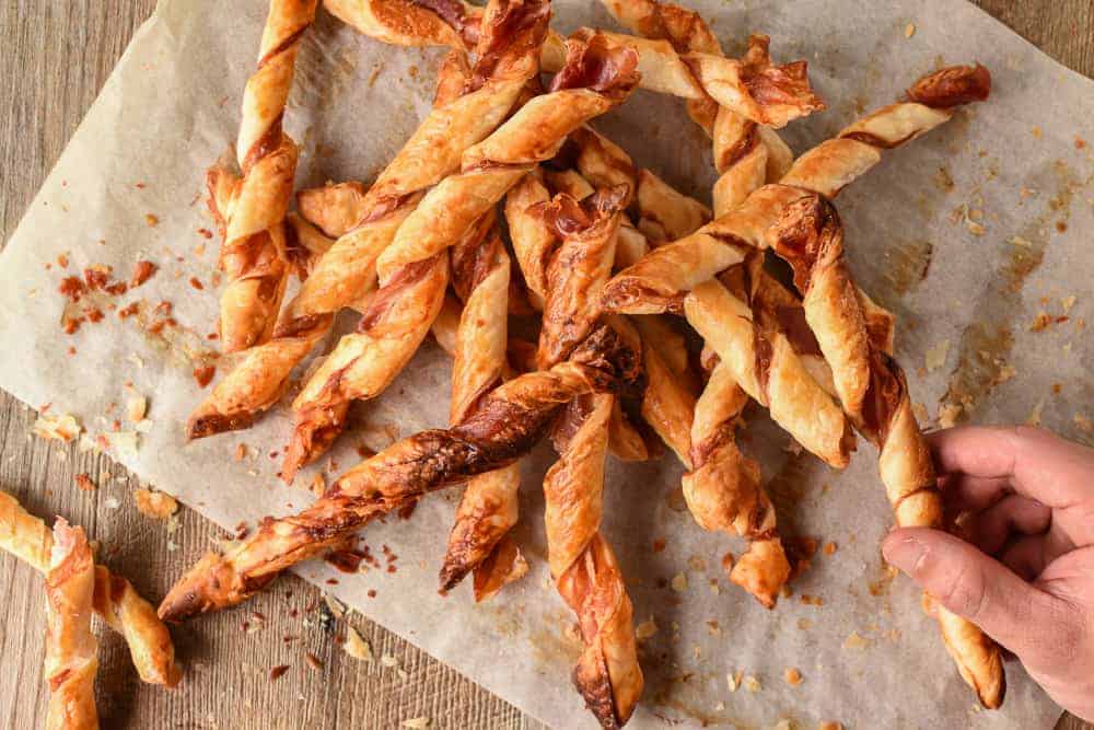 pile of pastry sticks with hand reaching in to take one.