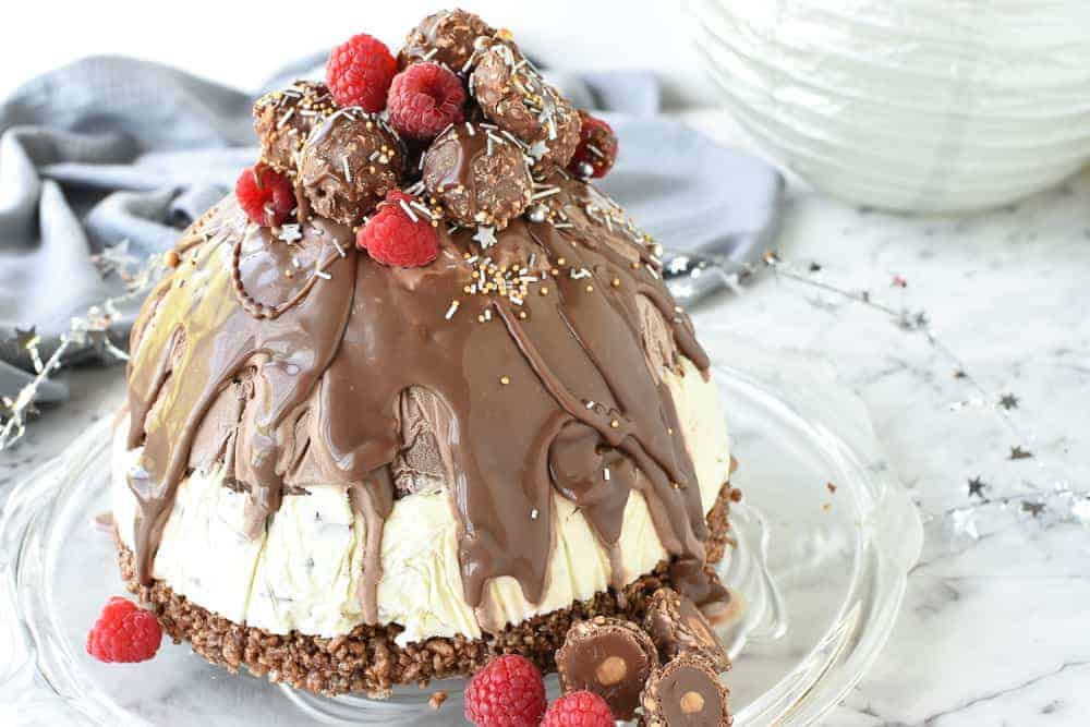 christmas ice cream pudding with chocolate drip decorated with chocolates and raspberries