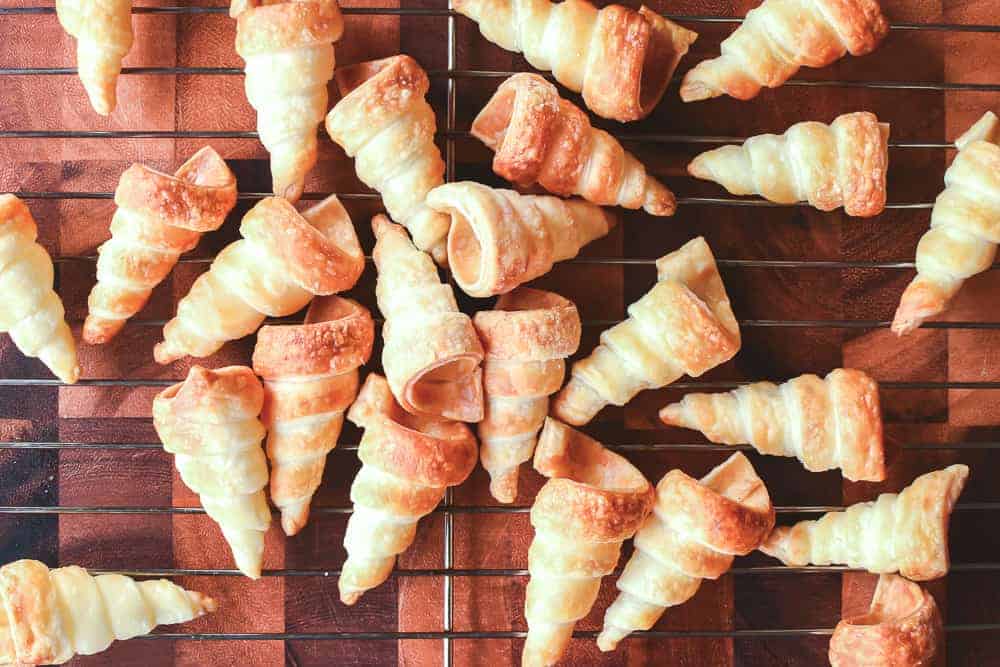 Lots of baked but empty pastry horn cases viewed from above.