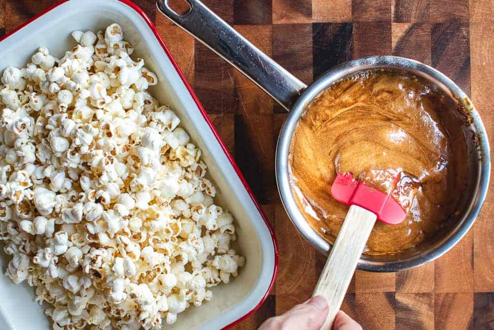 A pot of caramel and a tray of popcorn shown from overhead.