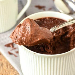 chocolate pudding in a teacups with a heaped spoonful of pudding resting on the top of the cup