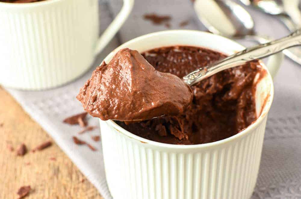 chocolate pudding in a teacups with a heaped spoonful of pudding resting on the top of the cup