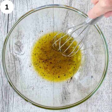 Oil and vinegar being whisked in a small bowl.