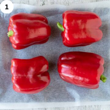 Four peppers on a baking sheet.