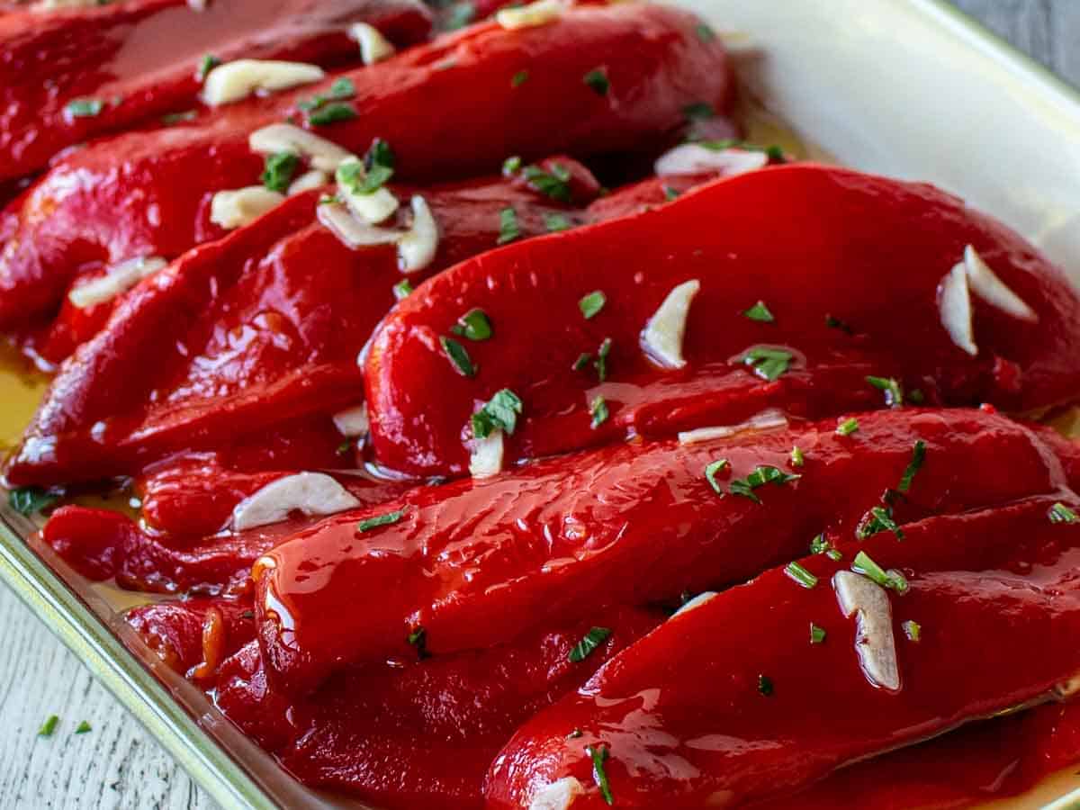Close up of slices of roasted peppers dress with oil and garlic.