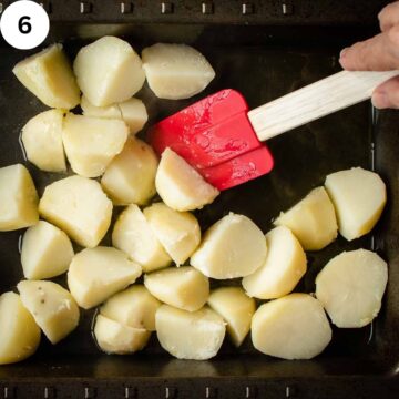 Stirring peeled potatoes in a baking pan with a red spatula.