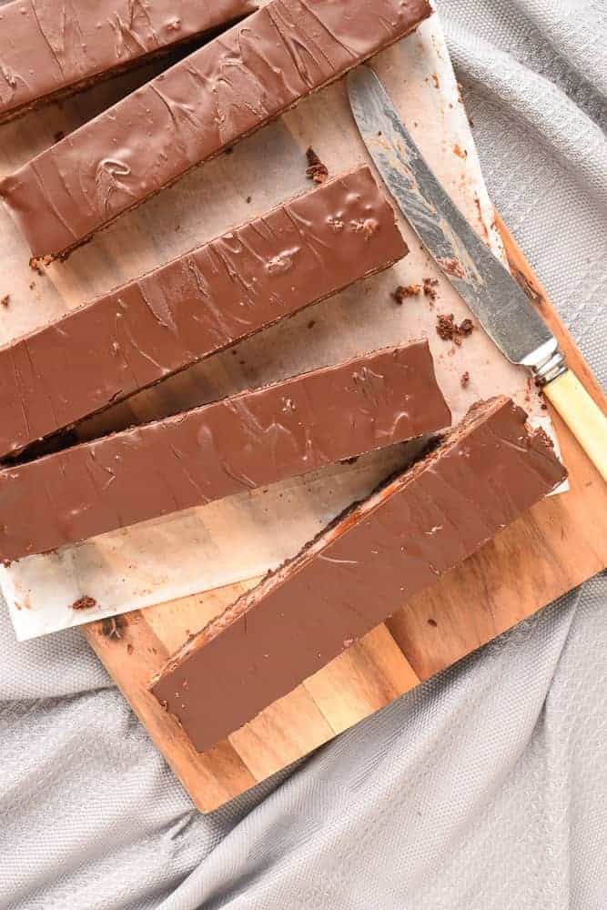 Five long slices chocolate cherry slice on a wooden board with vintage knife viewed from above