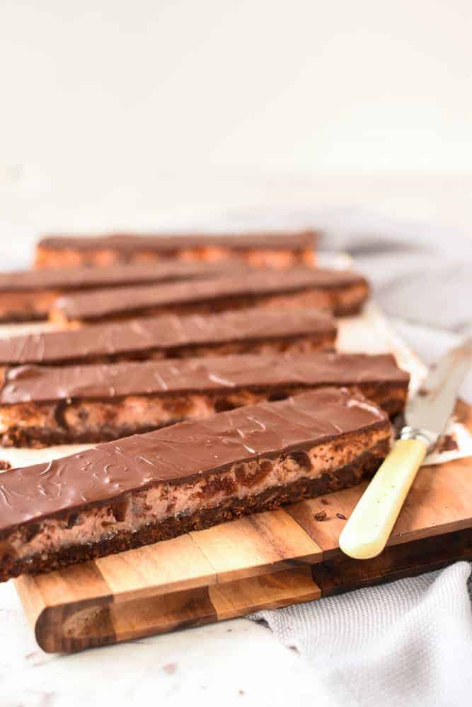 Six long slices of chocolate cherry slice on a wooden board with vintage knife viewed from 45 degree angle