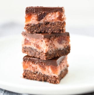 Three chocolate cherry slices stacked one on top of the other on a white plate viewed front on