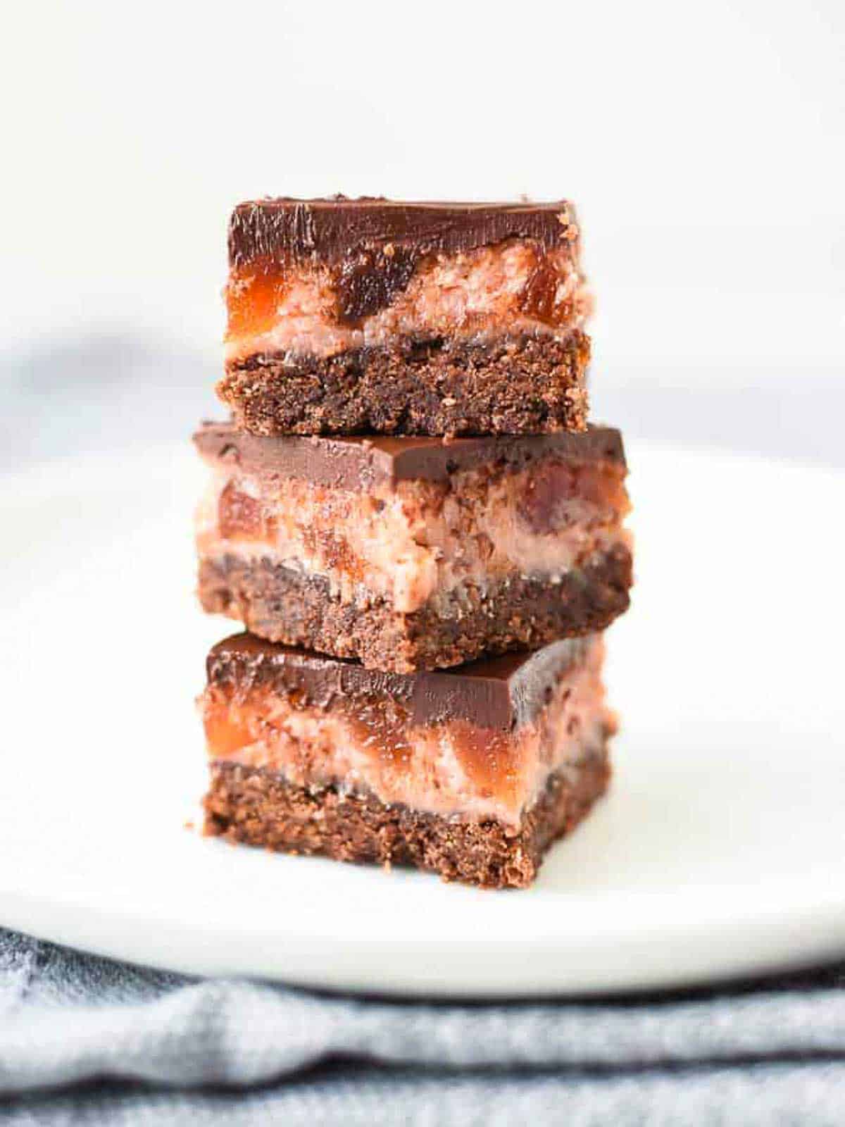 Three Cherry Ripe Bars stacked one on top of the other on a white plate viewed front on.