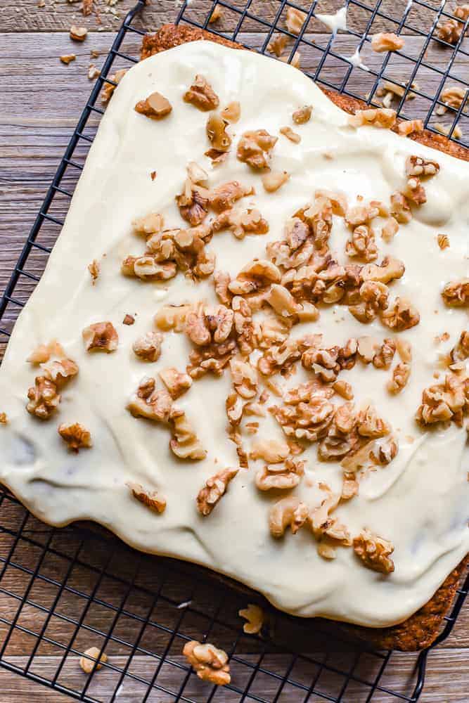 carrot cake with cream cheese frosting scattered with chopped walnuts viewed from above