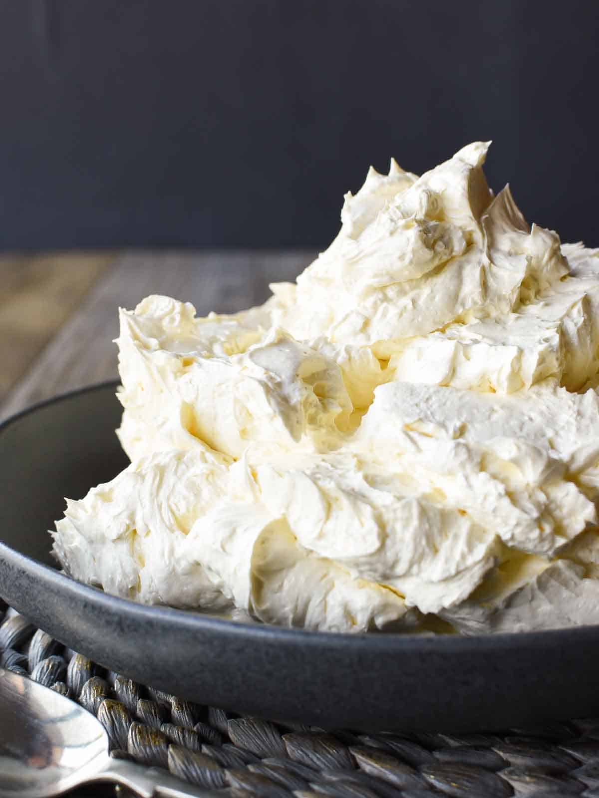 Italian meringue buttercream in black bowl viewed from the front on.