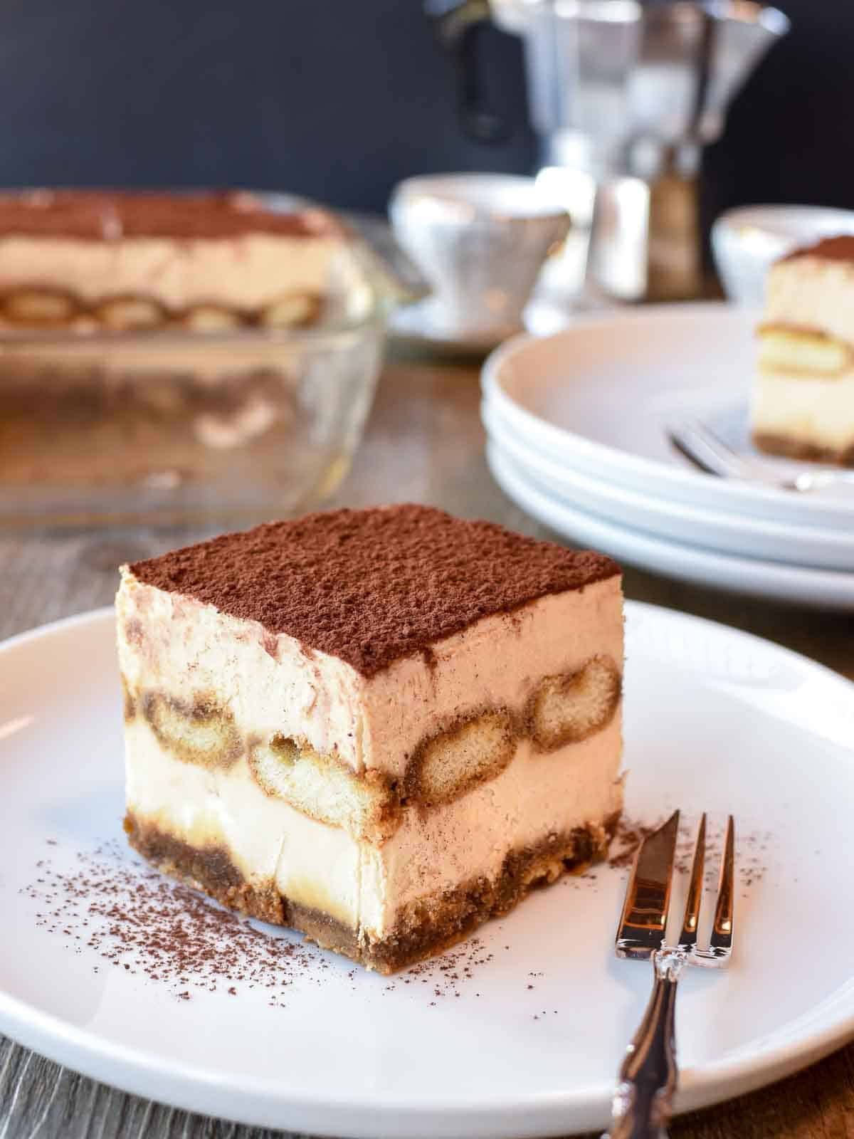 Square slice of Italian tiramisu on white plate.