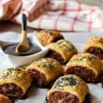 sausage rolls on baking paper with black sauce and red saucewith text above the image