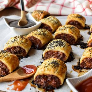 sausage rolls on baking paper with black sauce and red sauce