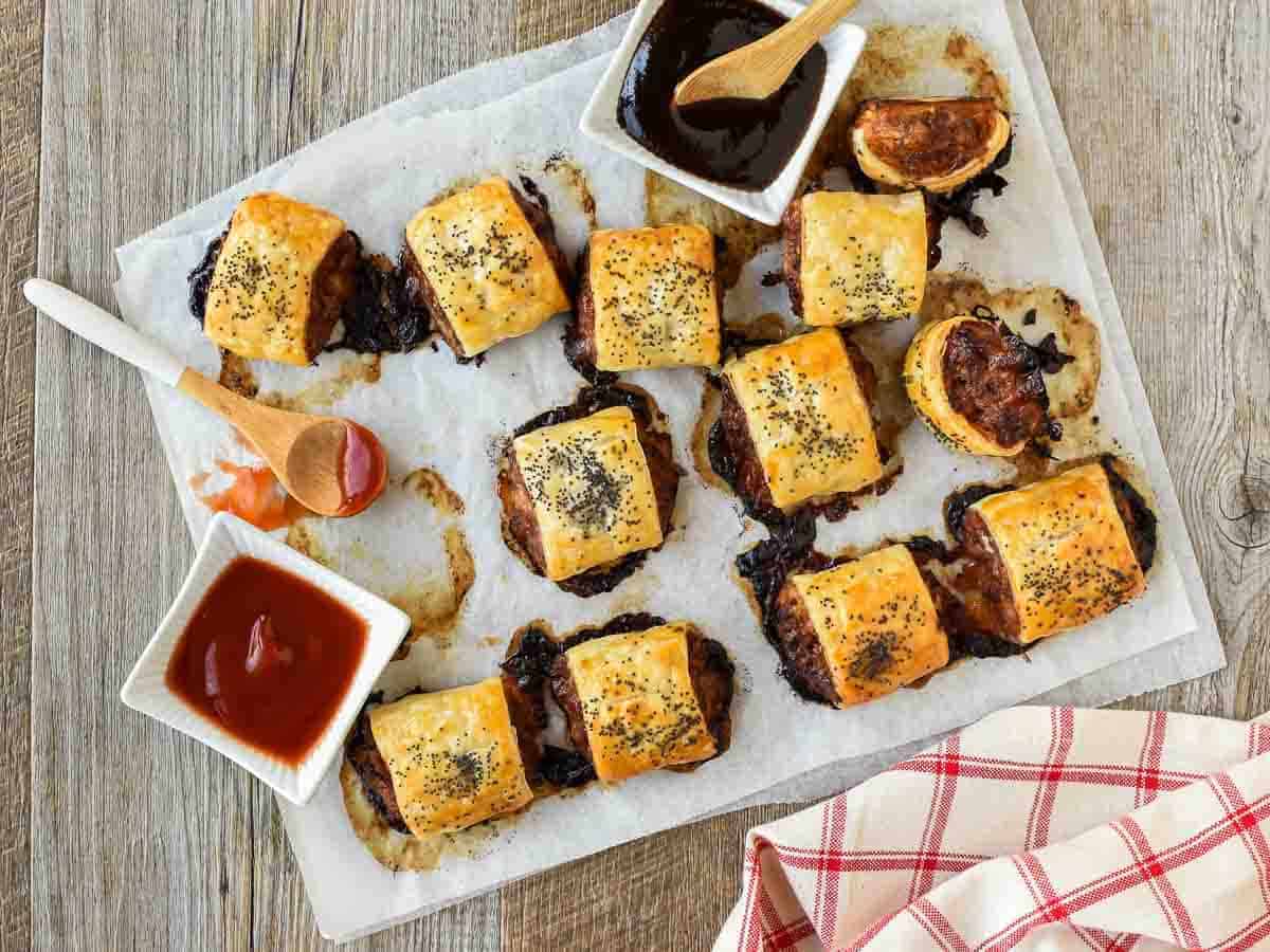 sausage rolls on baking paper with black sauce and red sauce viewed from above