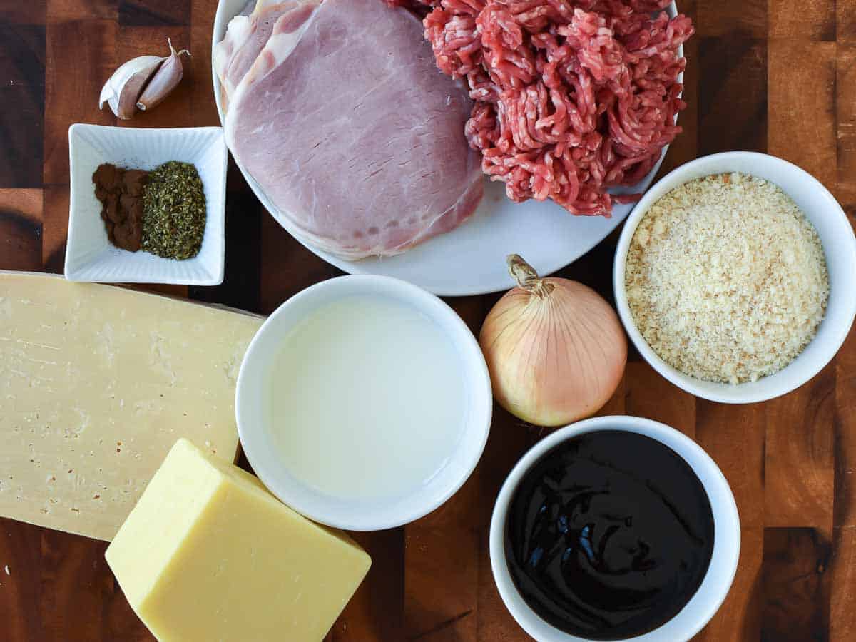 bacon, minced beef, bbq sauce, onion, blocks of cheese, garlic cloves, herbs and spices, breadcrumbs and milk viewed from above