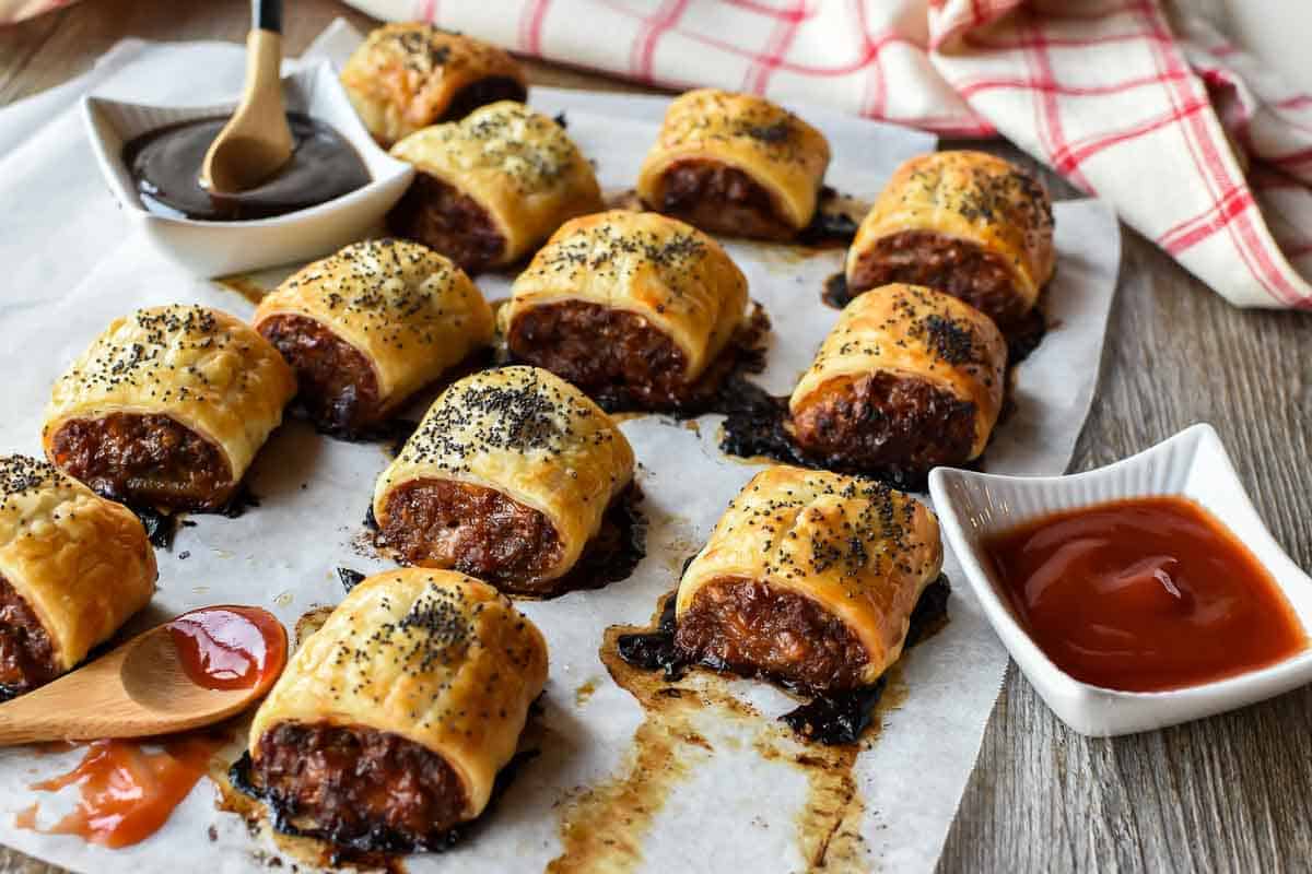 sausage rolls on baking paper with black sauce and red sauce