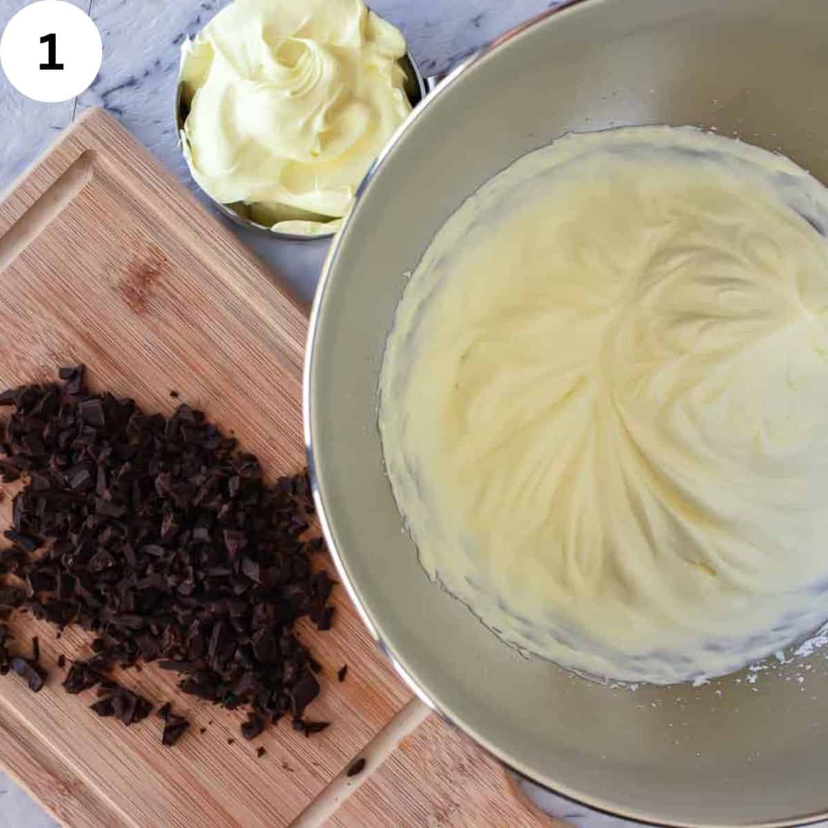 Overhead view of whipped cream in a stainless steel bowl with chopped chocolate and mascarpone cream on the side.