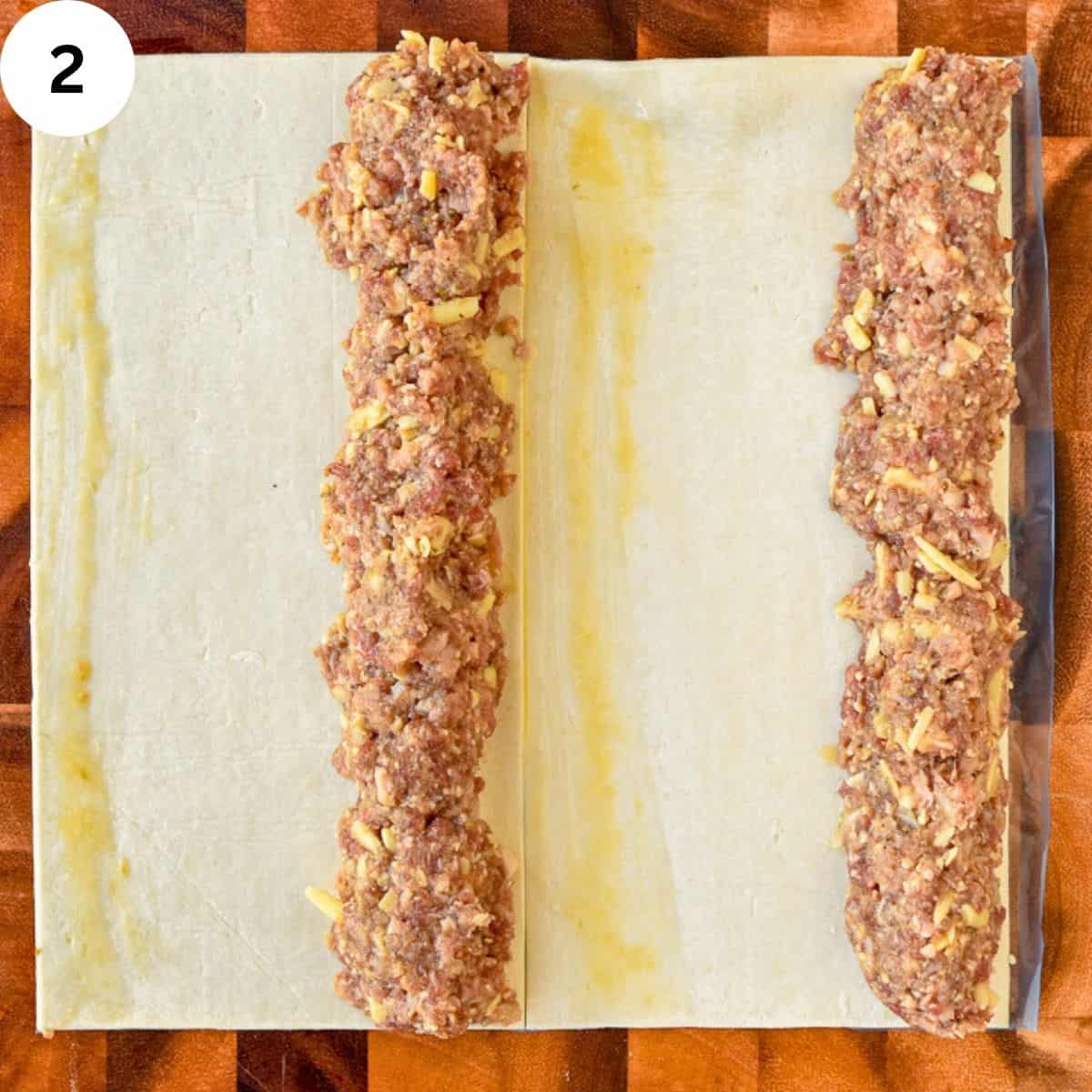 Meat filling arranged on puff pastry dough ready to be rolled.