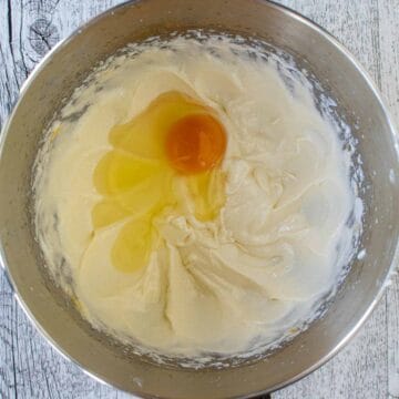 An egg on off white creamy mixture in stainless steel bowl.