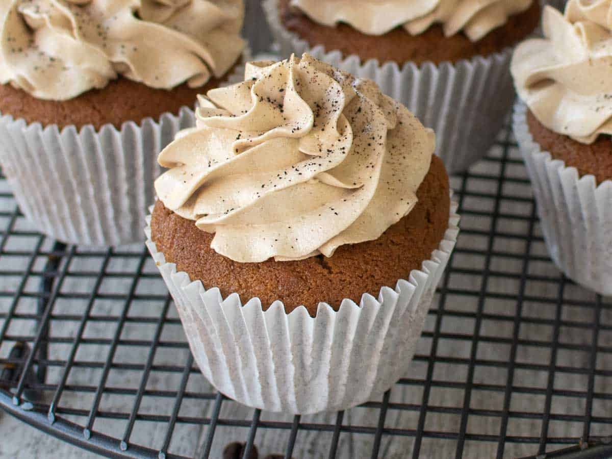 Close up of brown cupcake topped with swirl of off white cream.
