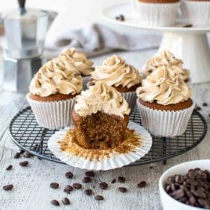 Coffee Cupcakes on black wire rack with a bite taken out of one cupcake.