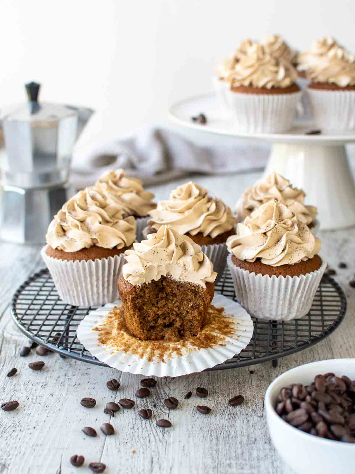 Coffee Cupcakes on black wire rack with a bite taken out of one cupcake.