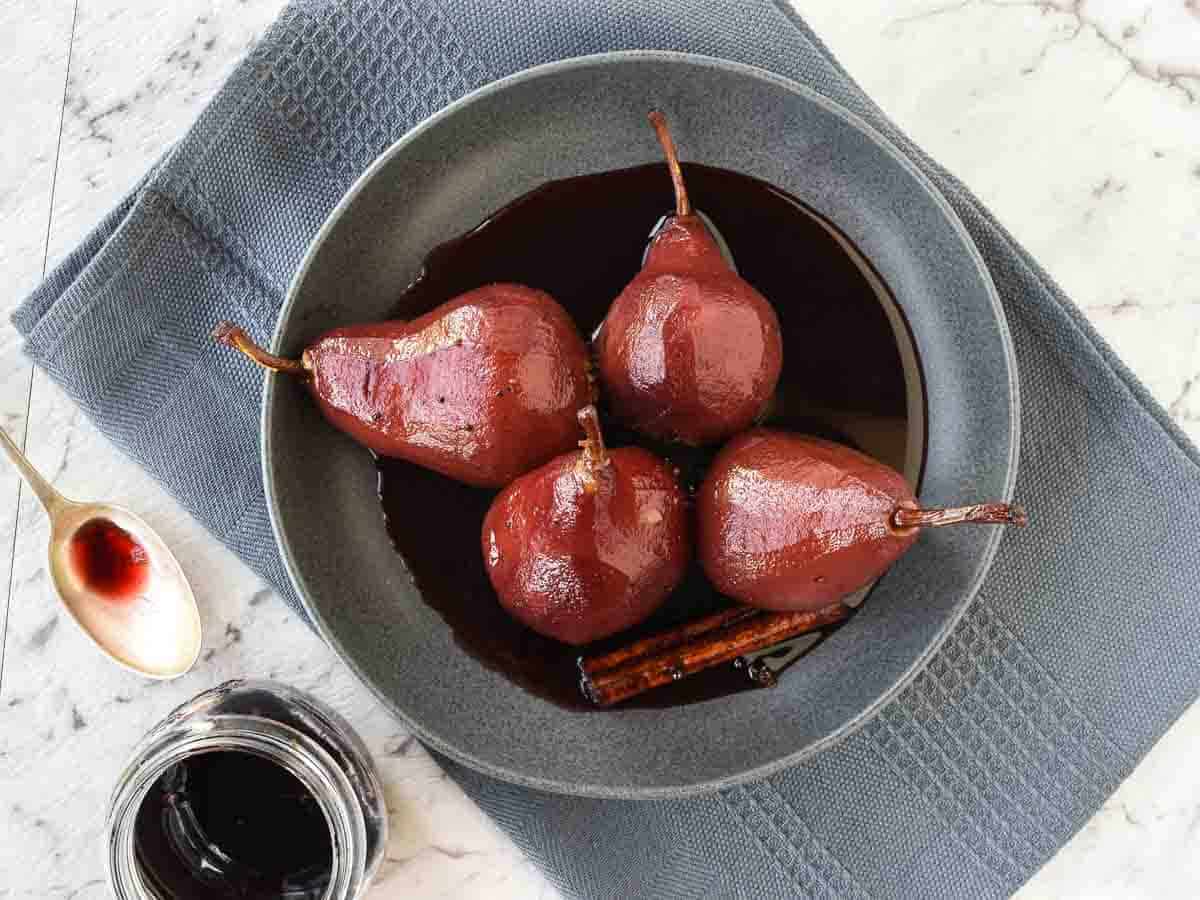 Four finished pears in a grey bowl viewed from above