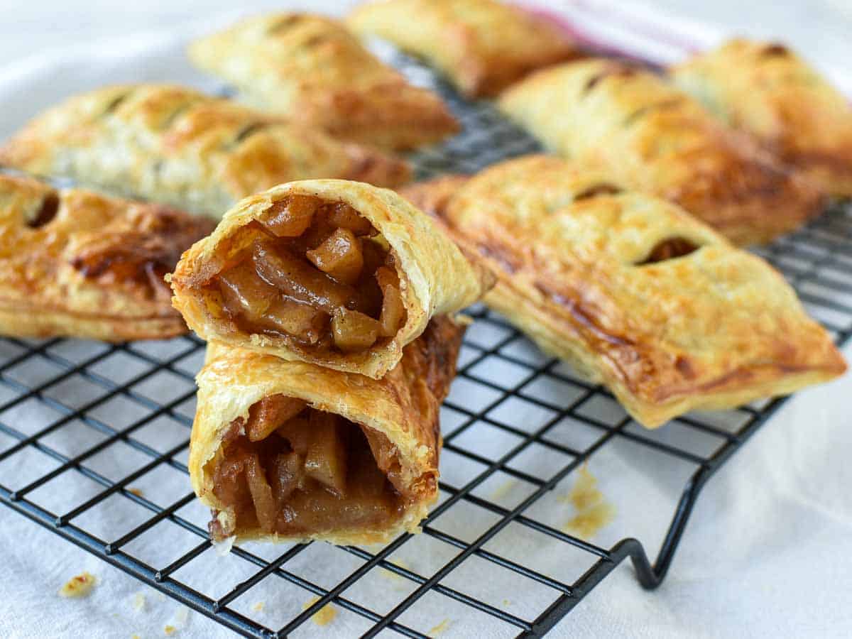 pastries on a black wire cooling rack with one cut in half to reveal the inside.